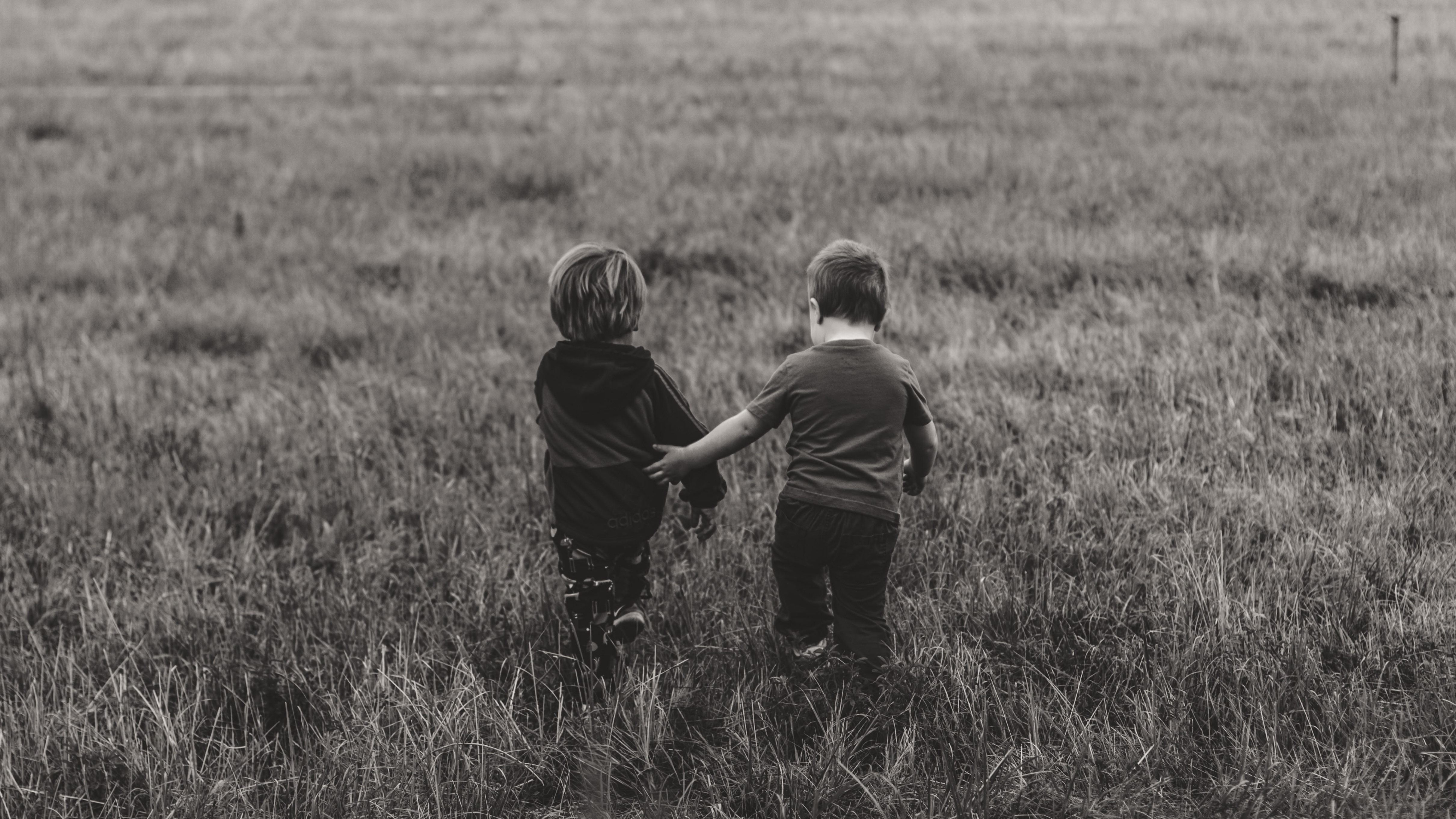 Two boys walking together in a field.