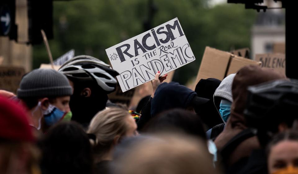 protestors at a Black Lives Matter march with the sign "Racism is the real pandemic"